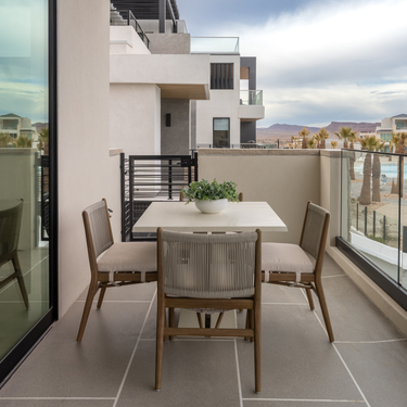 Dining area with a table and chairs on a balcony with a cityscape view.